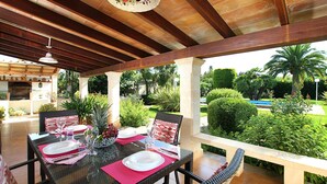 An outdoor patio with a dining table set for two, surrounded by lush greenery and a pool in the background. - MORENO. Fabulous garden, memorable holidays (Pollensa)