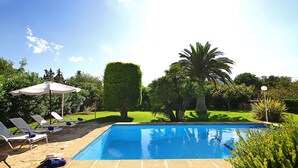 A swimming pool with lounge chairs and umbrellas, surrounded by well-maintained greenery and a clear sky. - MORENO. Fabulous garden, memorable holidays (Pollensa)