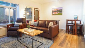 Un salon comprenant un canapé, un fauteuil, une table basse et un coin repas avec une table et des chaises.