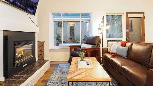 Un salon avec une cheminée, un canapé, une table basse et un téléviseur fixé au mur.