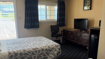 A hotel room with two beds, a desk, a television, and a window with curtains.