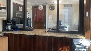 Un comptoir d’accueil avec une machine à café, un téléphone et un panneau indiquant les heures d’enregistrement.