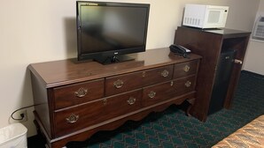 Une commode en bois sur laquelle sont posés un téléviseur à écran plat et un four à micro-ondes.