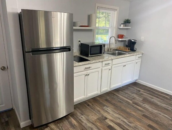 A kitchen with white cabinets, a stainless steel refrigerator, a microwave, and a sink. - Spacious King Bed Cottage at Veda Inn (Maggie Valley)