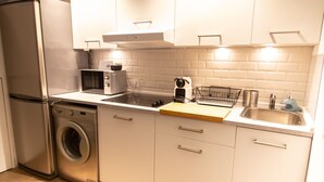 A compact kitchen with a washing machine, a toaster, a sink, and a microwave.