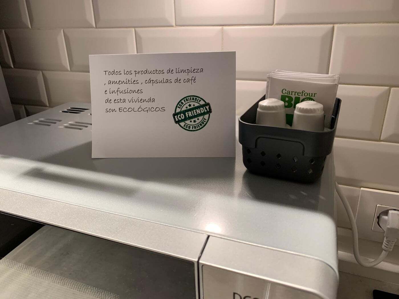 A bathroom counter with a sign stating the products are eco-friendly, a basket with bottles, and a power outlet.