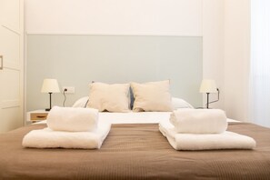 A hotel room with a bed, two bedside tables, two lamps, and a window.