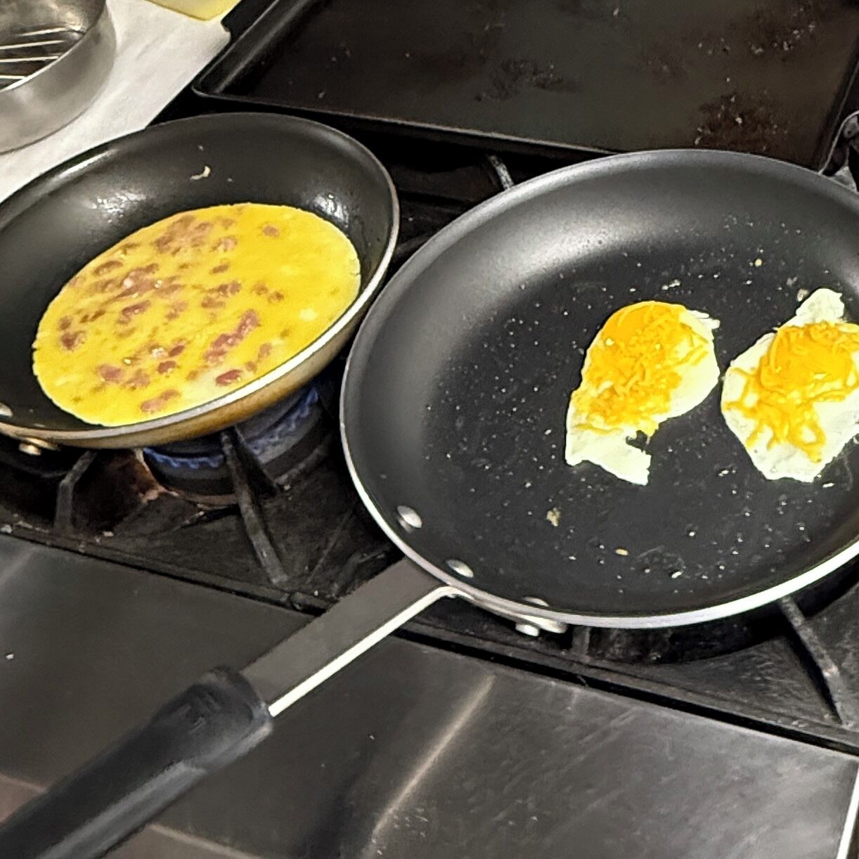 Two frying pans on a stove with food in them.