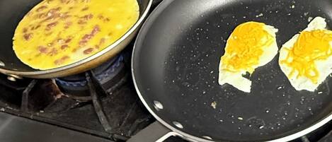 Two frying pans on a stove with food in them.
