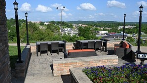 Une terrasse extérieure avec des murs en pierre, du mobilier d’extérieur et des lampadaires décoratifs.