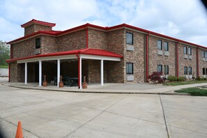 A multi-story building with a brick facade, a covered outdoor seating area, and a red roof. - Giles Hotel Inn & Suites (Pulaski)
