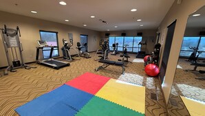 Une salle de sport équipée de tapis de course, de vélos elliptiques et de ballons d’exercice.