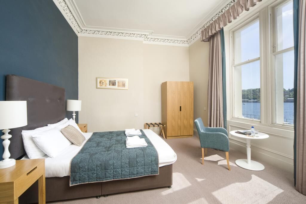 A hotel room with a bed, a desk, a chair, a wardrobe, and a window with a view.