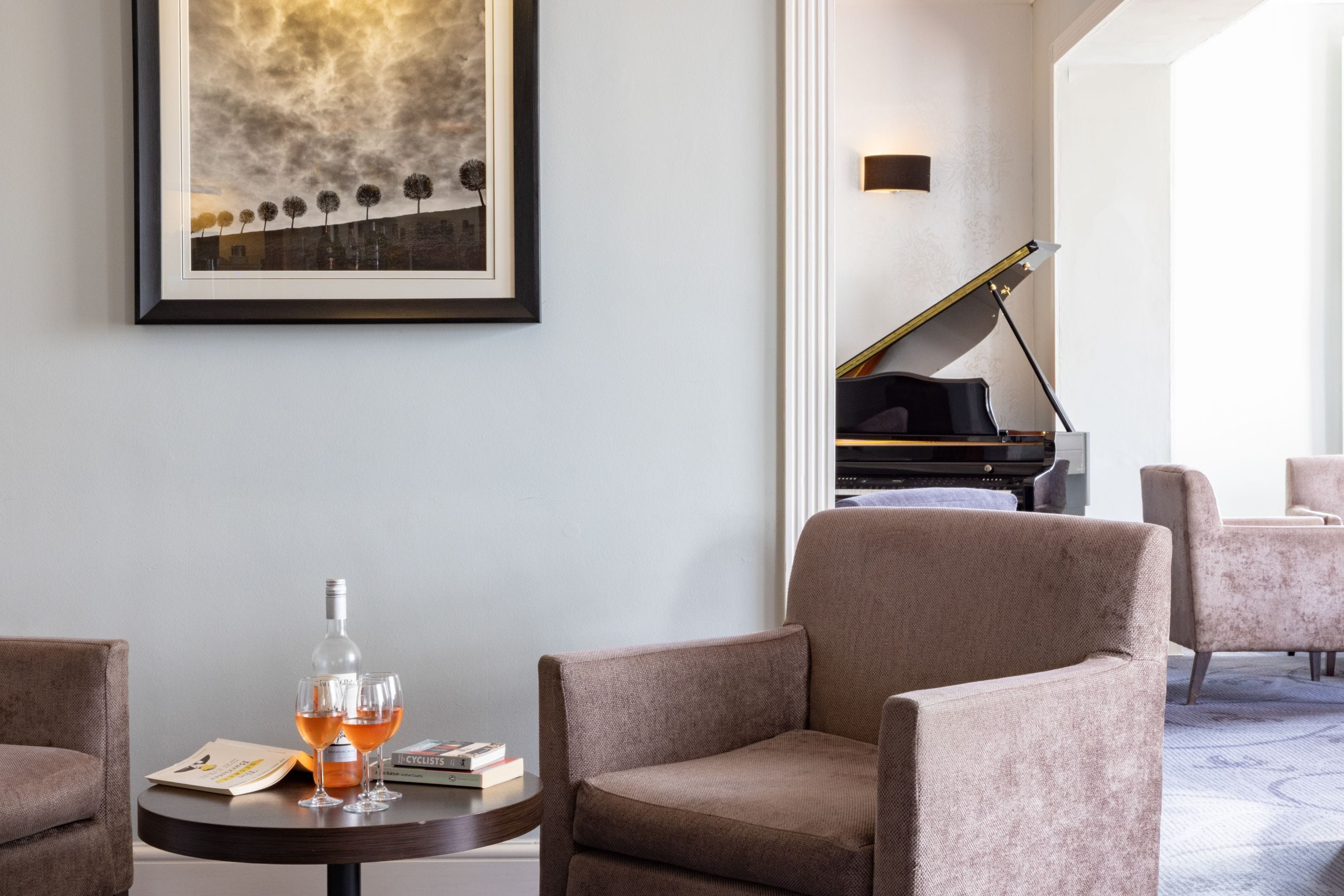 A hotel lobby with a framed artwork, a piano, and seating areas.