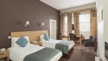 A hotel room with two beds, a desk, a chair, a TV, and a phone on the nightstand.
