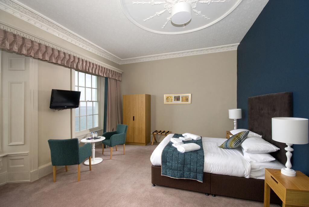 Une chambre d’hôtel avec un lit, une télévision, un bureau et une chaise.