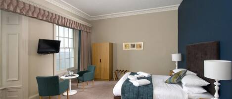 Une chambre d’hôtel avec un lit, une télévision, un bureau et une chaise.