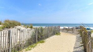 A sandy beach path with a wooden fence leading to the ocean, under a clear blue sky. - Seven Seas - Recently Remodeled Ocean Block 1 Bedroom! (Ocean City)
