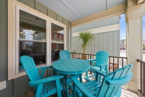 Une terrasse couverte avec des fauteuils Adirondack turquoise et une table ronde.