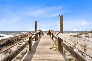 Une promenade en bois qui mène à une plage d’où l’on a une vue dégagée sur l’océan.