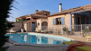 A swimming pool with lounge chairs, a fenced patio area, and a building with blue shutters. - Villa Catalane (Saint-André)