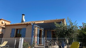 Uma casa com telhado de telhas, chaminé e varanda coberta.