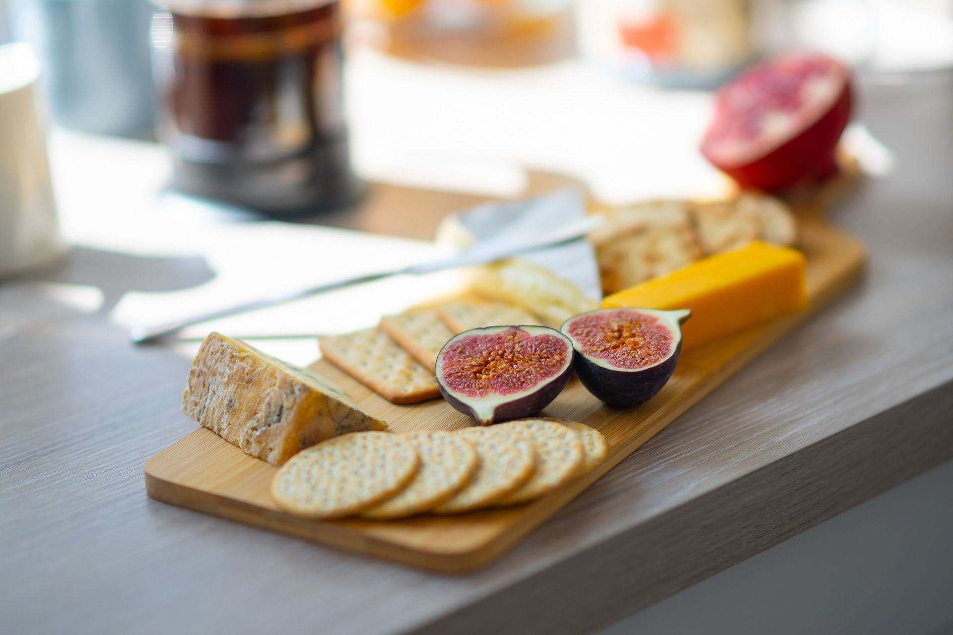 Una tabla de madera con varios quesos, galletas y higos sobre una mesa.