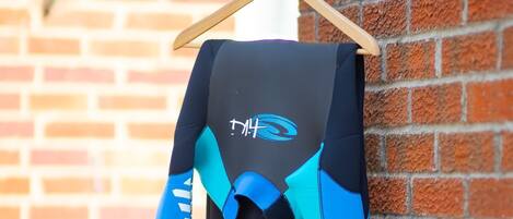 A wetsuit hanging on a wooden hanger against a brick wall.