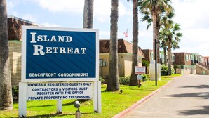 Segnaletica per Island Retreat, che indica appartamenti al mare. Include un avviso per proprietari, ospiti registrati, fornitori e visitatori: registrazione presso l'ufficio richiesta. Proprietà privata, divieto di accesso.