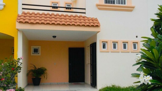A two-story building with a tiled roof, a balcony, and a small window. - Casa Vacacional en la Playa (Mazatlán)