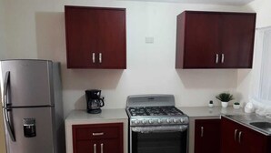 A compact kitchen with a refrigerator, stove, and cabinets. - Casa Vacacional en la Playa (Mazatlán)