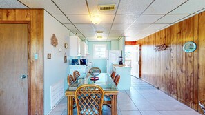 Una cocina amplia con armarios de madera, una mesa de comedor con sillas y vista al área de estar.