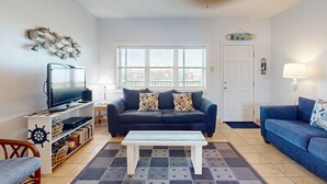 A living room with a TV, sofa, and coffee table. - Walk to Sandfest, Shared Pools, Boardwalk to Beach (Port Aransas)