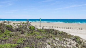 A beach with a lifeguard tower and a sign indicating a beach area. - Walk to Sandfest, Shared Pools, Board Walk to Beach (Port Aransas)