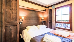 Camera d'albergo con una testiera in legno, un letto con lenzuola bianche, due lampade sui comodini e una finestra con tende.