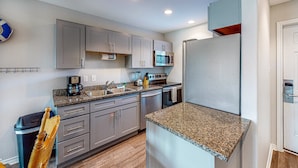 A modern kitchen with grey cabinets, stainless steel appliances, and granite countertops. - Walk to Sandfest , Shared Pool, Board Walk to Beach (Port Aransas)