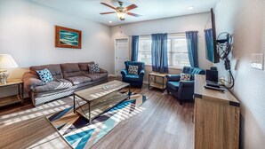 A living room with a sofa, armchair, coffee table, and a ceiling fan. - Walk to Sandfest , Shared Pool, Board Walk to Beach (Port Aransas)