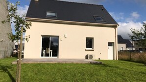 Una casa a un piano con tetto scuro, un'entrata e una piccola finestra.