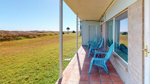 A covered patio with a view of a grassy field and distant hills. - Walk to Sandfest,  Shared Pools, Boardwalk to the Beach (Port Aransas)