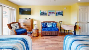 A room with two beds, a sofa, a dining table, and a TV on the wall. - Walk to Sandfest, Shared Pools, Boardwalk to the Beach (Port Aransas)