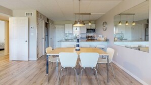 A modern kitchen with white cabinets, a central island, and pendant lighting. - Walk to Sandfest, Shared Pool, Boardwalk to the Beach (Port Aransas)