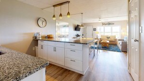 A kitchen with granite countertops, white cabinets, and pendant lighting. - Walk to Sandfest, Shared Pool, Boardwalk to the Beach (Port Aransas)