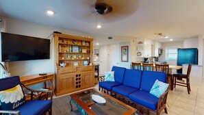 Un salon avec un canapé bleu, un meuble en bois et un téléviseur à écran plat.