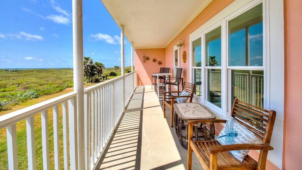 Un balcon donnant sur un paysage verdoyant, une table avec des chaises et un banc.