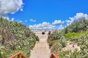 A sandy beach path leading to the ocean with a clear sky and clouds. - Walk to Sandfest, Shared Pool, Boardwalk to the Beach (Port Aransas)