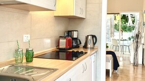 A modern kitchen with white cabinets, a wooden countertop, and a view to the dining area.