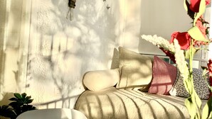 A room with a bed, a wall clock, and a window with sunlight casting shadows.