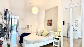 A modern bedroom with a bed, bedside table, lamp, and a view of the hallway.