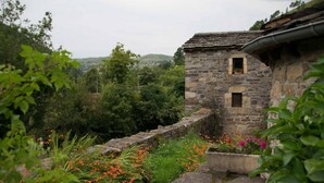 A stone building with a small window and a stone wall. - Molino de Yera (Vega de Pas)
