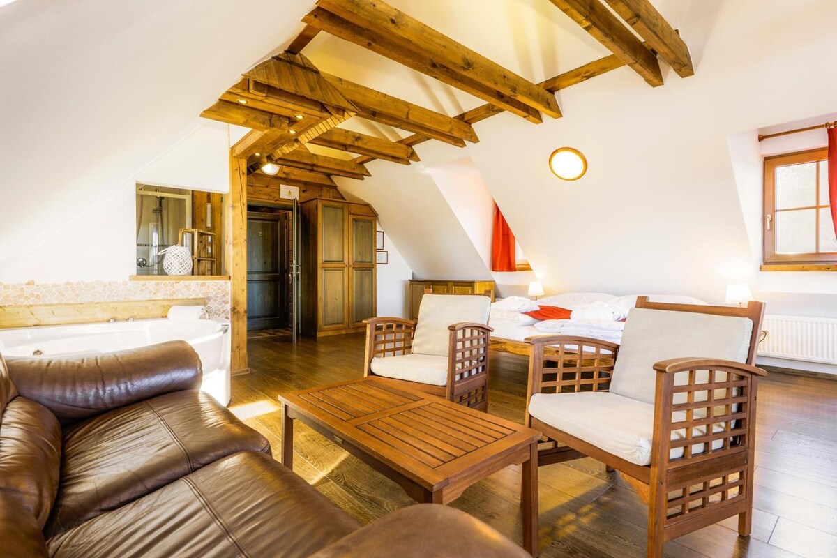 Un cuarto acogedor con techo de madera, un sofá, una mesa y una cama con vista al exterior.